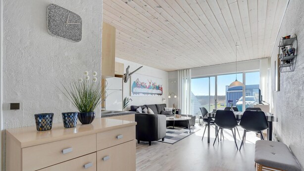 Moderni keittiö, jossa on ruokailutila, suuret ikkunat ja näkymä ulos.