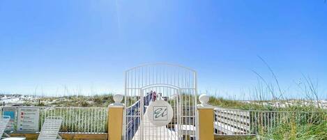 Ein Eingang direkt am Strand mit einem Tor, einer Holzterrasse und freiem Blick auf den Strand.