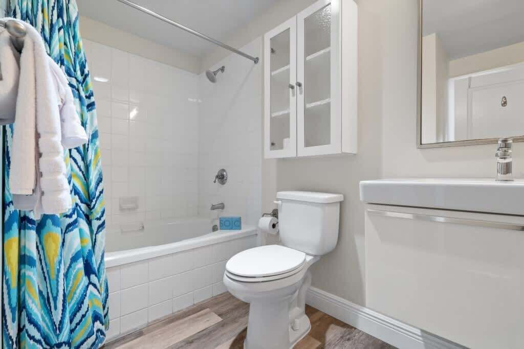 Een badkamer met een wit toilet, een douche, een bad en een kast.