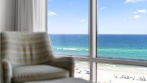 A room with a large window overlooking a beach.