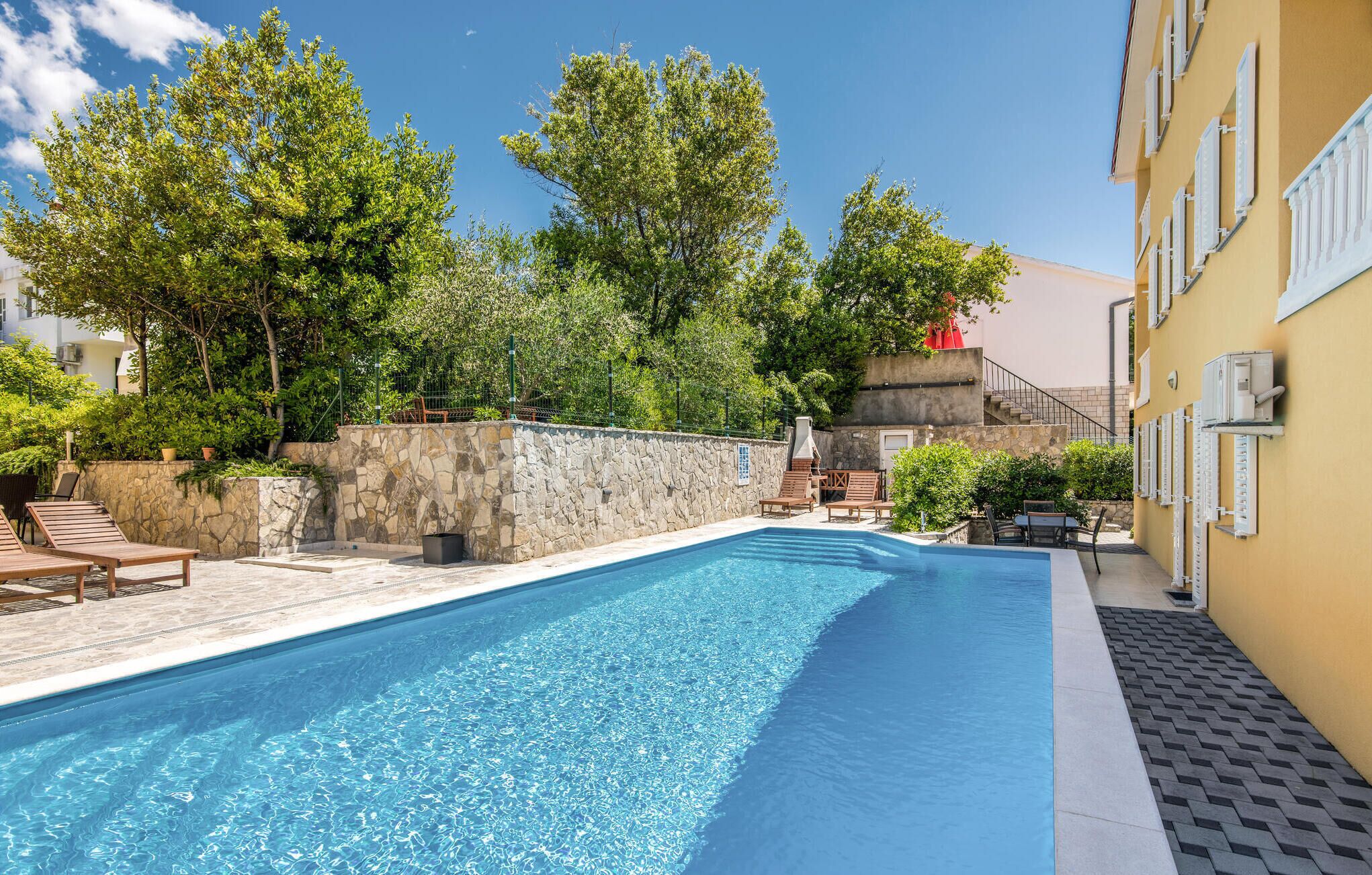A swimming pool with lounge chairs and a stone wall.