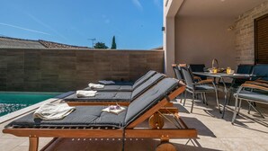A poolside area with lounge chairs and a dining table. - Amazing home in Barban (Barban)