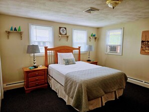 Un dormitorio ordenado con una cama, dos mesitas de noche y un reloj de pared.