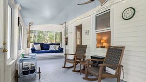 En veranda med en blå soffa, gungstolar och ett litet bord.
