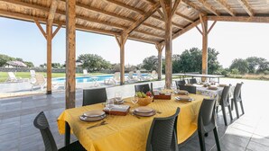An outdoor dining area with a pool and lounge chairs in the background. - Pet friendly home in Ragusa (Ragusa)