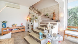 A staircase with a stone wall, a wicker sofa, a wooden bench, and a small table with decorative items. - Beach front home in Casuzze-Finaiti with sauna (Casuzze-Finaiti)
