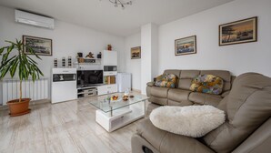 Un salon moderne avec un canapé beige, une table basse en verre et une plante en pot.