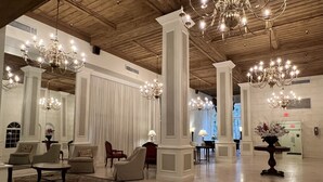 En rummelig lobby med høje lofter, lysekroner og siddeområder.