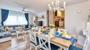 Ein modernes Wohnzimmer mit einer Couch, einem Esstisch, Stühlen und einem Fernseher.
