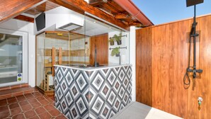 Ein moderner Außenbereich mit Kochgelegenheit, Rückwand mit Muster, Holz-Pergola und Holz-Zaun.