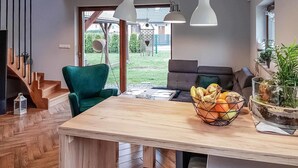 Eine moderne Küche mit einem Holztisch, einem grünen Stuhl und einer Obstschale.