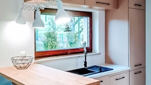 Eine moderne Küche mit Fenster, weißen Schränken und einer Holz Arbeitsplatte.