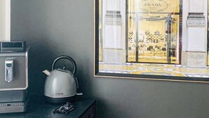 Cozinha com chaleira, máquina de café e vista emoldurada para a vitrine da loja Prada.