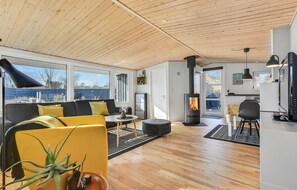 Un salon moderne avec une cheminée, un plafond en bois et de grandes fenêtres.
