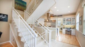A spacious kitchen with modern appliances, a dining area, and a staircase leading to another level. - Siesta Sunrise II-Between the Beach and Village (Siesta Key)