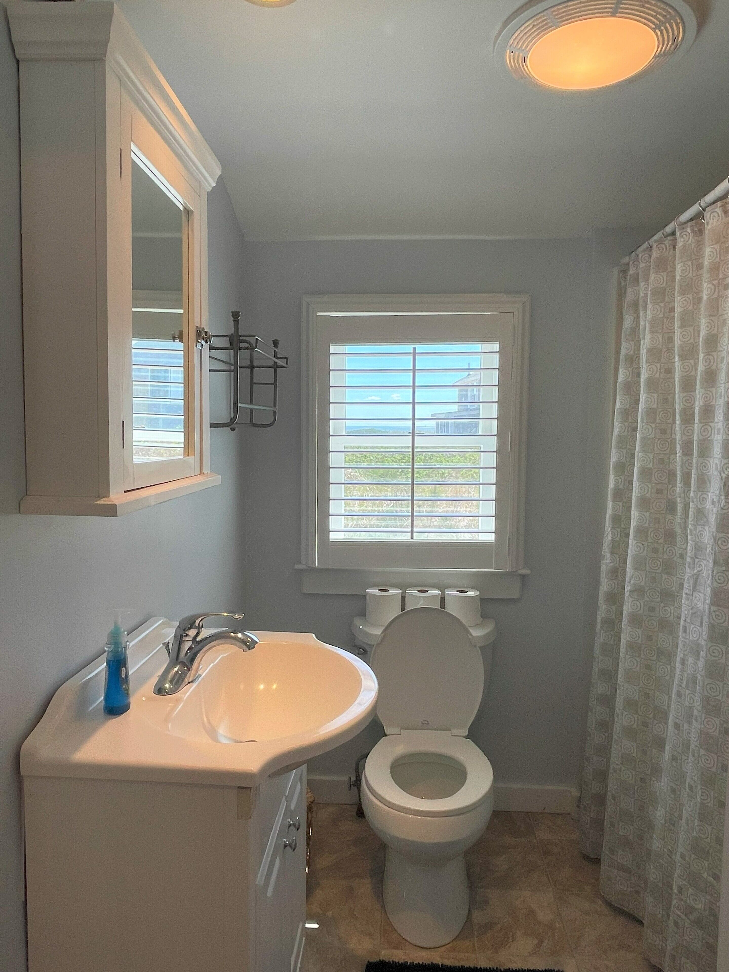 A bathroom with a sink, toilet, and window.