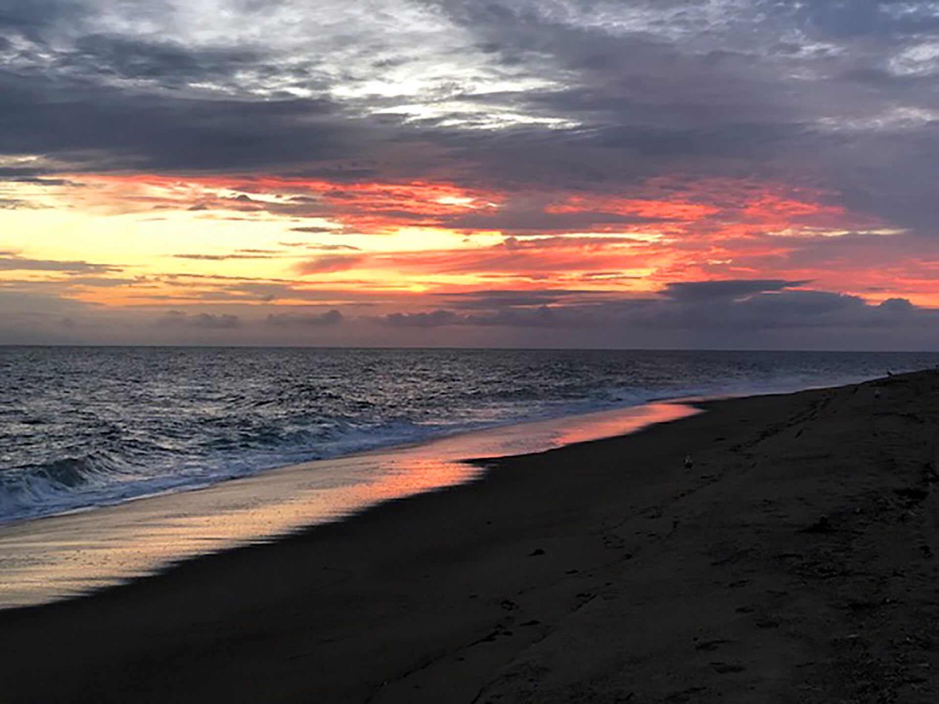 A beach with a sunset over the ocean.