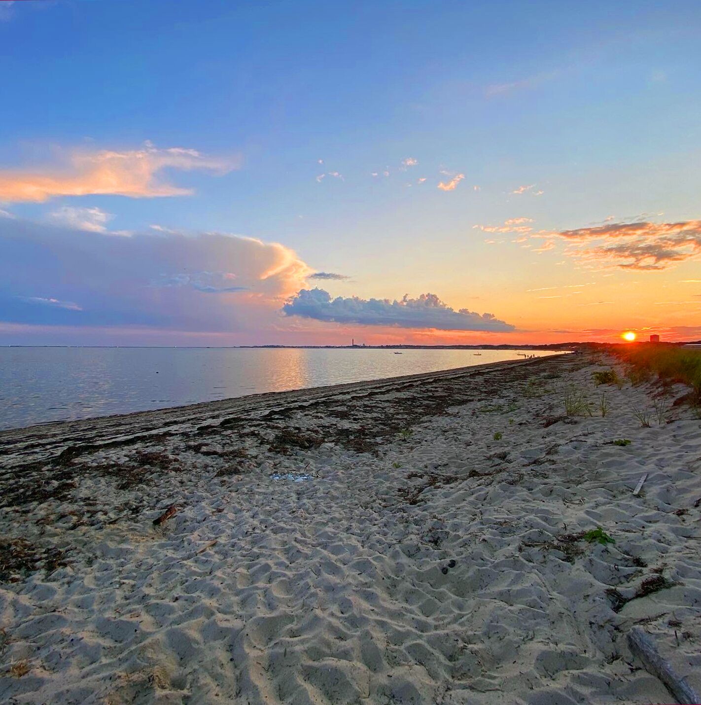 Ein Strand mit sandigem Ufer und ruhiger See bei Sonnenuntergang.