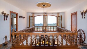 Un magnifique escalier en bois, avec une rampe, mène à un balcon d’où l’on peut admirer le paysage.