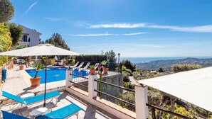 Un espace piscine offrant une vue dégagée sur la mer et les collines en arrière-plan.