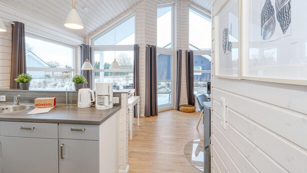 Eine moderne Küche mit einer Holztheke, großen Fenstern und Blick auf eine verschneite Landschaft.