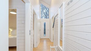 Ein schmaler Korridor mit Holzwänden und einer Tür zu einem Zimmer mit einem Fenster.