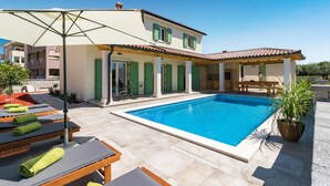 A poolside area with a pool, lounge chairs, and a covered seating area. - Gorgeous home in Peroj (Peroj)