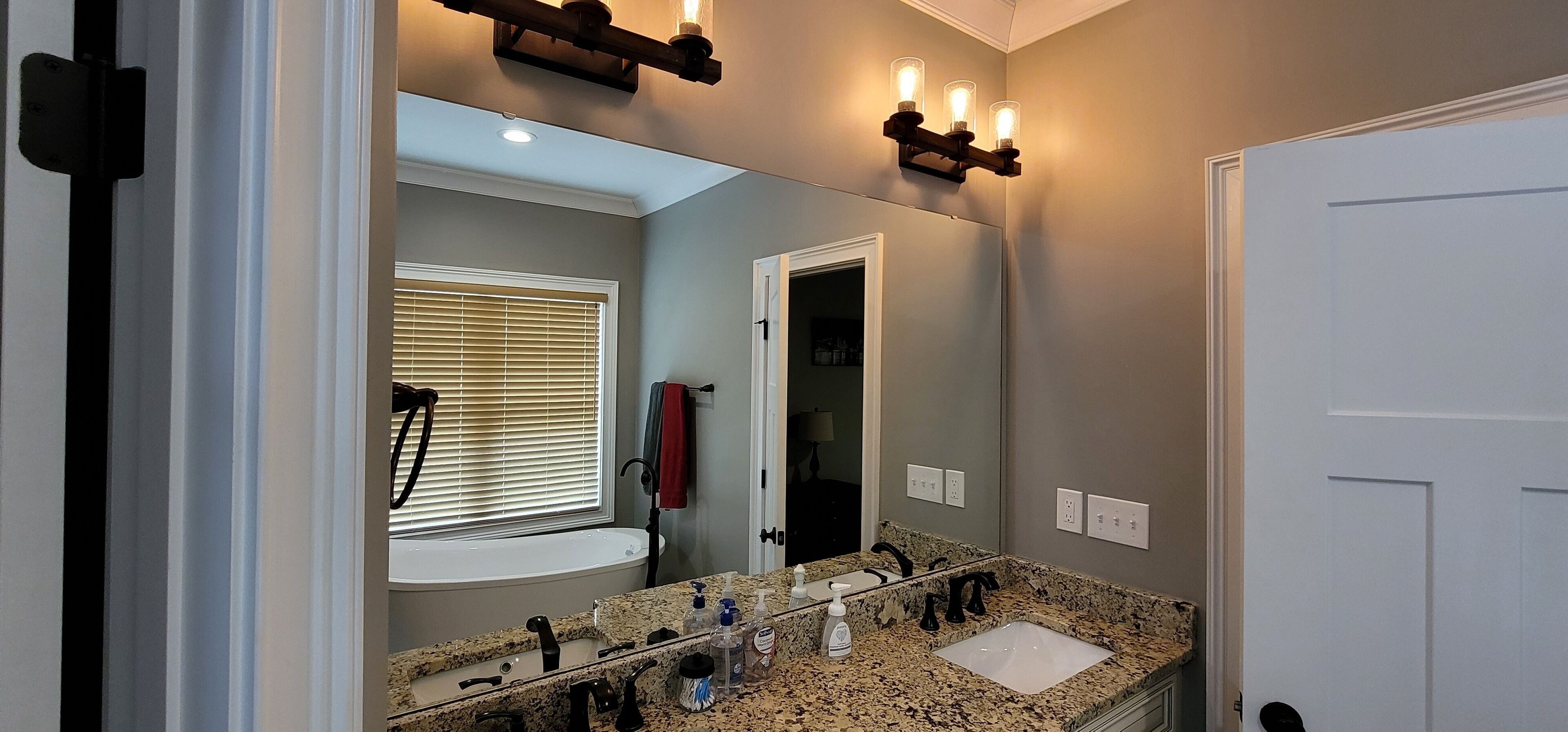 A bathroom with a granite countertop, a sink, a mirror, and a shower.