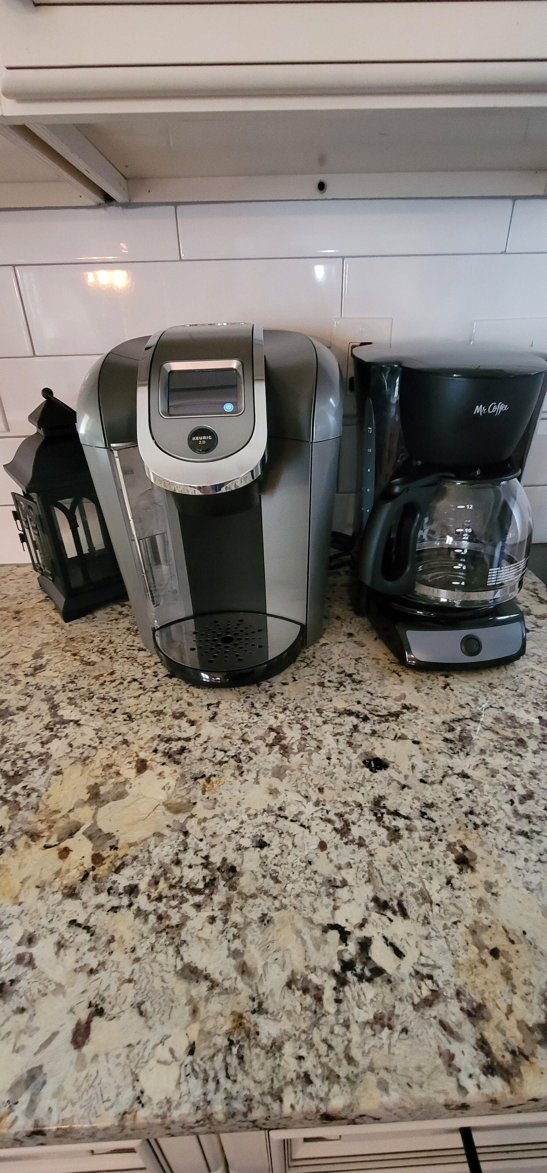 A kitchen with a coffee maker and a coffee pot on a granite countertop.
