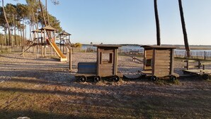 Une plage avec des structures de jeux en bois, notamment un toboggan et un petit bâtiment muni de roues.