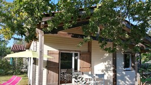 Une terrasse en bois avec des meubles d’extérieur, une porte-fenêtre coulissante et un patio couvert.