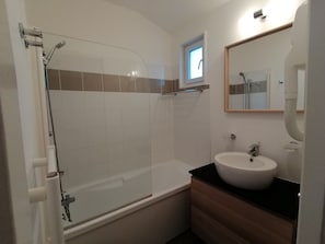 Un bagno con doccia vetrata, vasca, lavandino e specchio.