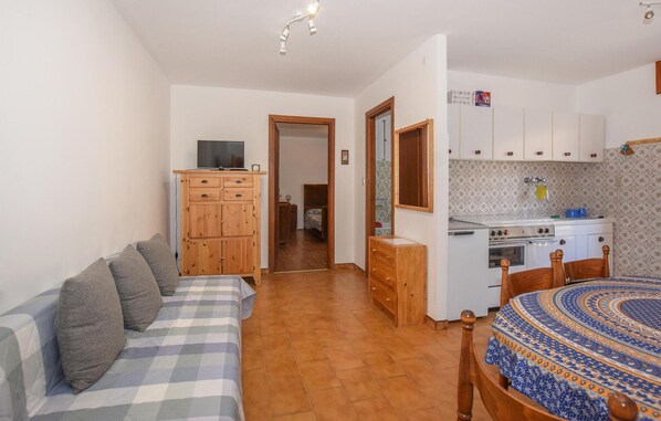 A compact living space with a sofa, wooden cabinets, a kitchenette, and a dining area.