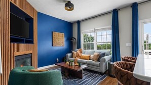 Una sala de estar con chimenea, televisor, sofá y mesa de centro.