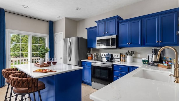 Una cocina moderna con gabinetes azules, electrodomésticos de acero inoxidable y una isla blanca.
