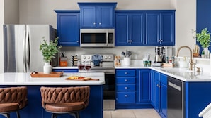 Una cocina moderna con armarios azules, electrodomésticos de acero inoxidable y una isla central con asientos.