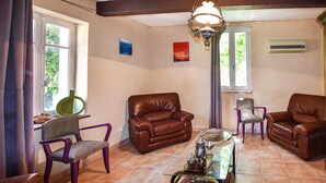 Una sala de estar con dos sofás de cuero marrón, una mesa de centro de vidrio y una butaca morada.