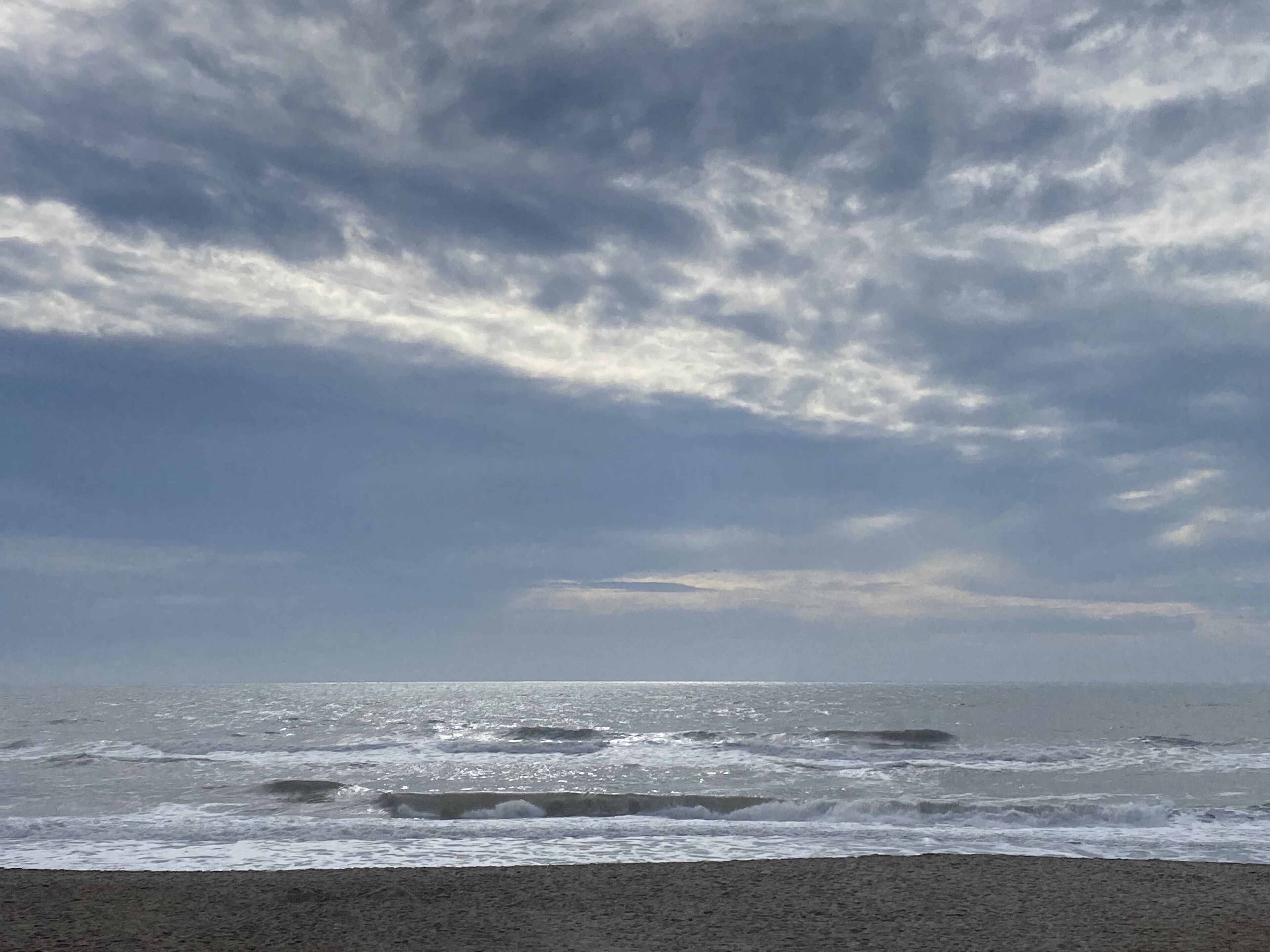 Una playa con olas y un cielo nublado.