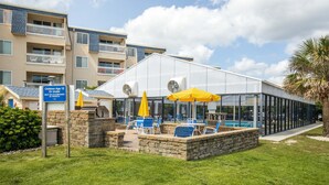 A building with a glass facade, outdoor seating with yellow umbrellas, and a sign indicating children under 12 must be accompanied by parents. - Tommy's Bahama! in A Place At The Beach Resort on the OCEAN & the BEST pools! (Atlantic Beach)
