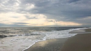 A beach with waves and a cloudy sky. - Tommy's Bahama! in A Place At The Beach Resort on the OCEAN & the BEST pools! (Atlantic Beach)