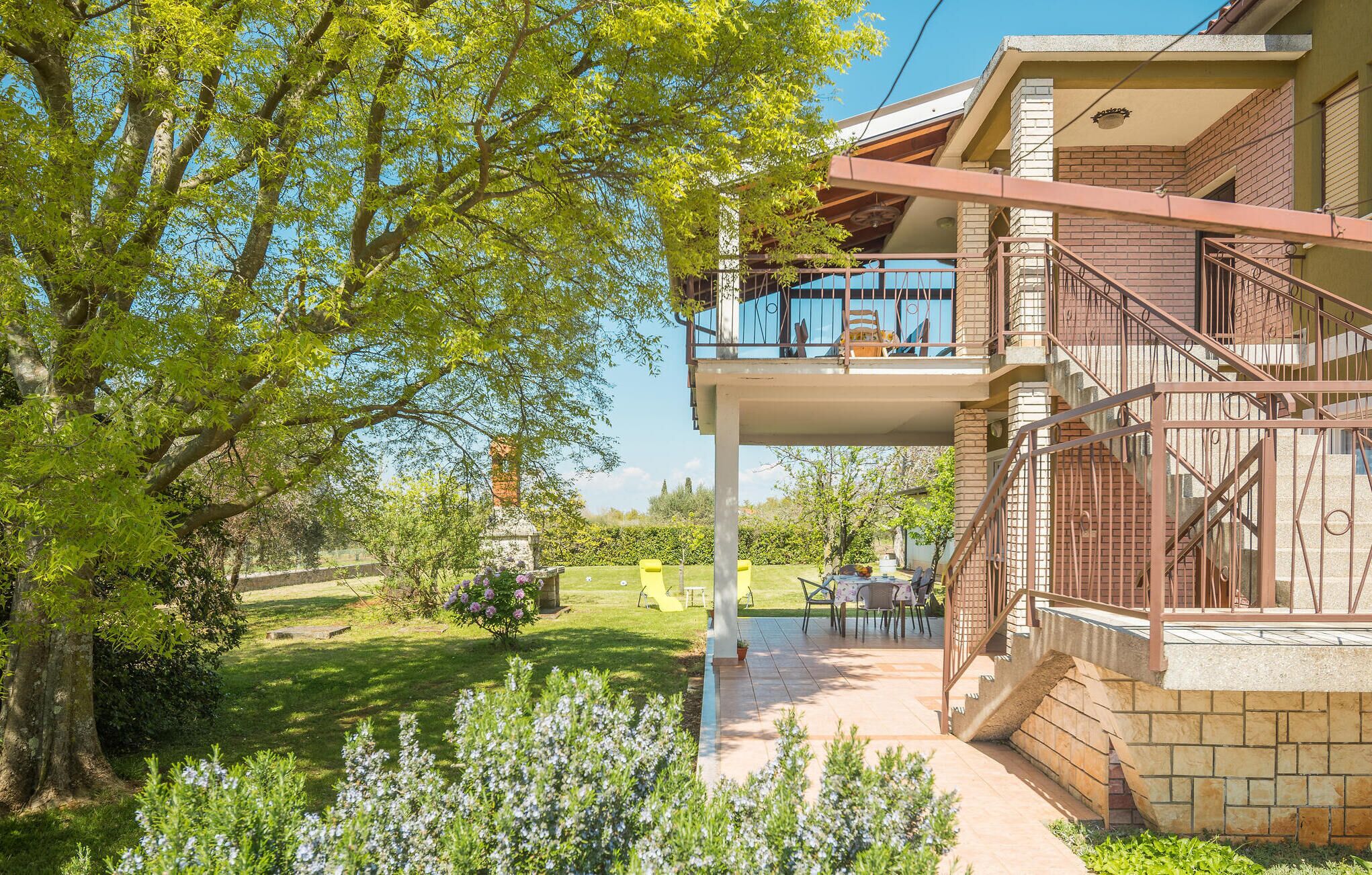 Un bâtiment à deux étages doté d’un balcon, d’un jardin et d’un escalier en pierre.