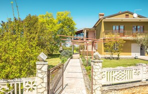 Stroll through the beautifully maintained garden, featuring a variety of trees and shrubs, to the entrance of this modern home.