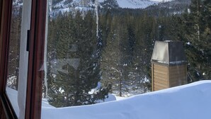Eine verschneite Berglandschaft, mit von einem Fensterrahmen hängenden Eisstücken.