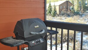 A barbecue grill on a wooden deck with a view of a cabin and trees. - Mountainside condo in a Colorado playground! (Frisco)