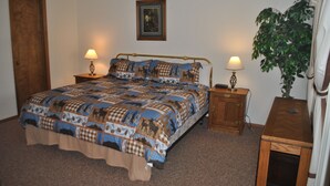 A bedroom with a large bed, two bedside tables with lamps, a wooden nightstand, a framed picture on the wall, and a potted plant. - Mountainside condo in a Colorado playground! (Frisco)