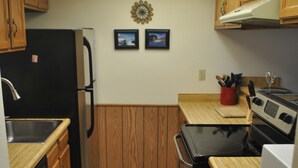 A compact kitchen with wooden cabinets, a black refrigerator, a stove, and a dishwasher. - Mountainside condo in a Colorado playground! (Frisco)