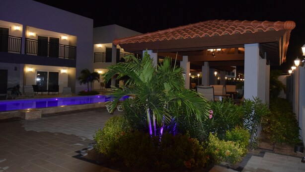Un patio con piscina, una zona de estar cubierta y un edificio con varios balcones.