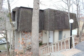 A two-story building with a stone facade, a small porch, and a staircase leading to the entrance. - Lake front property with huge dock connected to Margaritaville (Osage Beach)