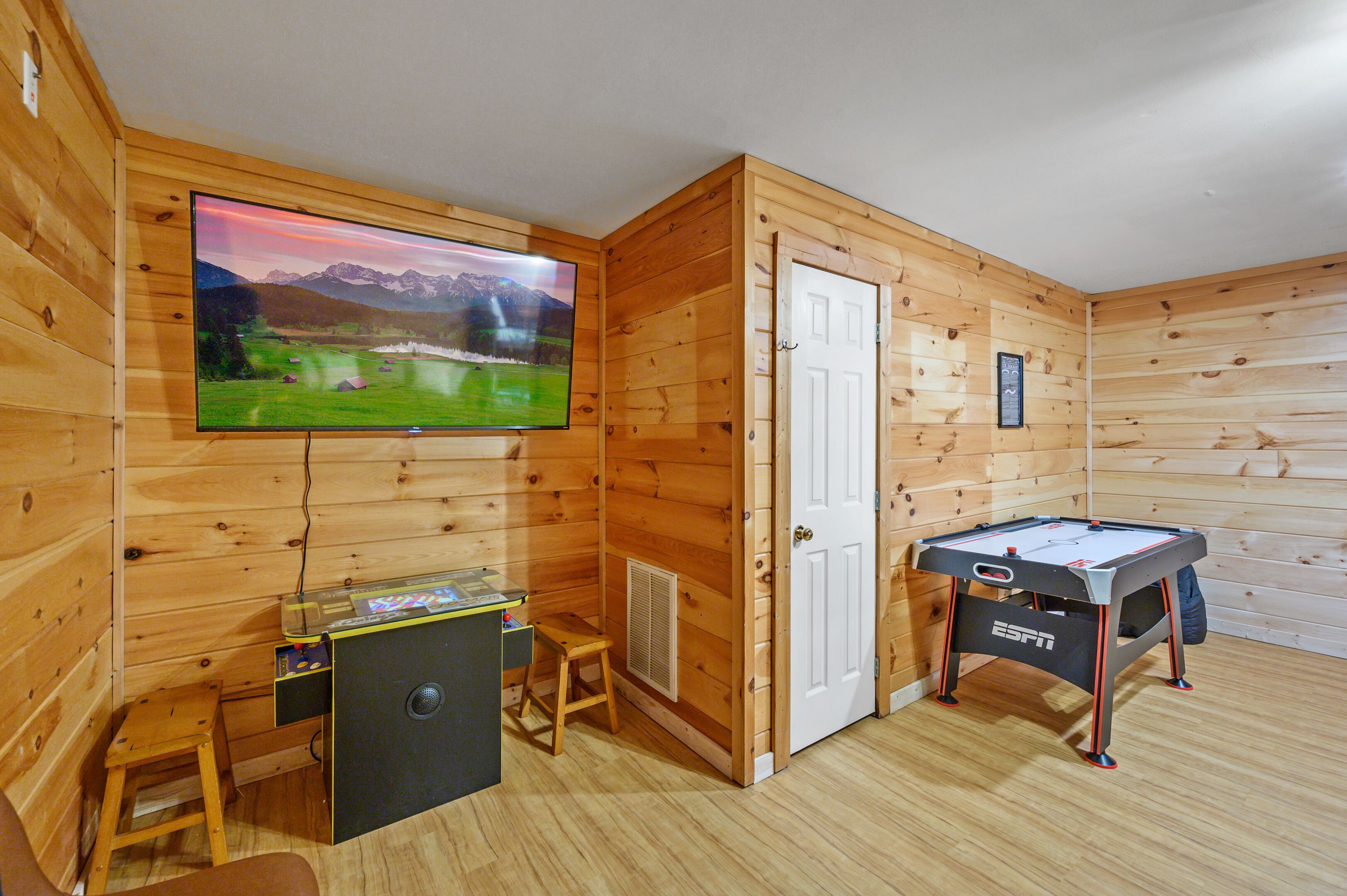 A wooden room with a television, a pool table, and a small table with a computer.