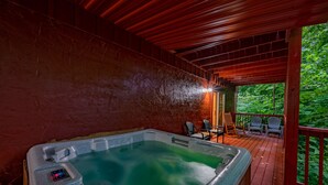 Een hottub op een houten terras met stoelen en uitzicht op groen.